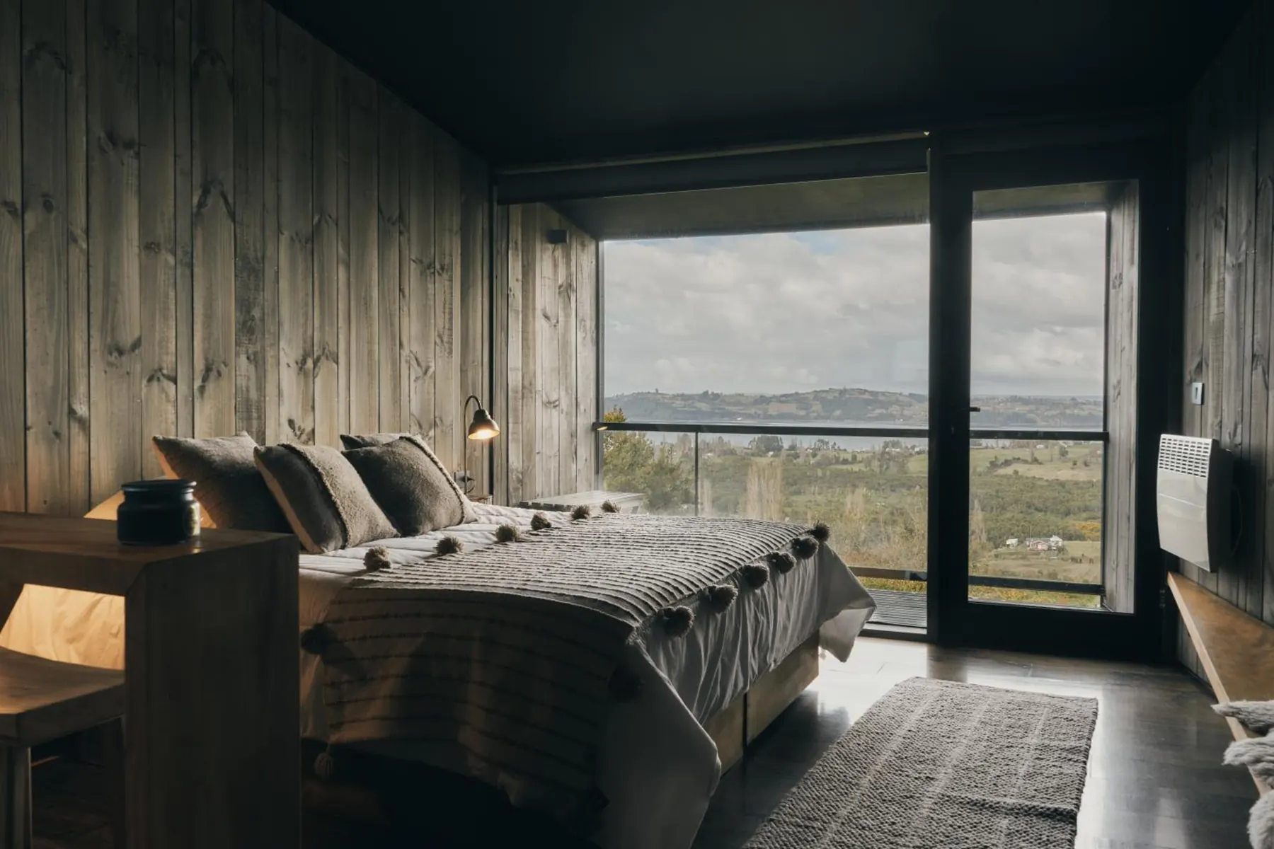 Habitación con cama king, muros de madera y ventanal al mar
